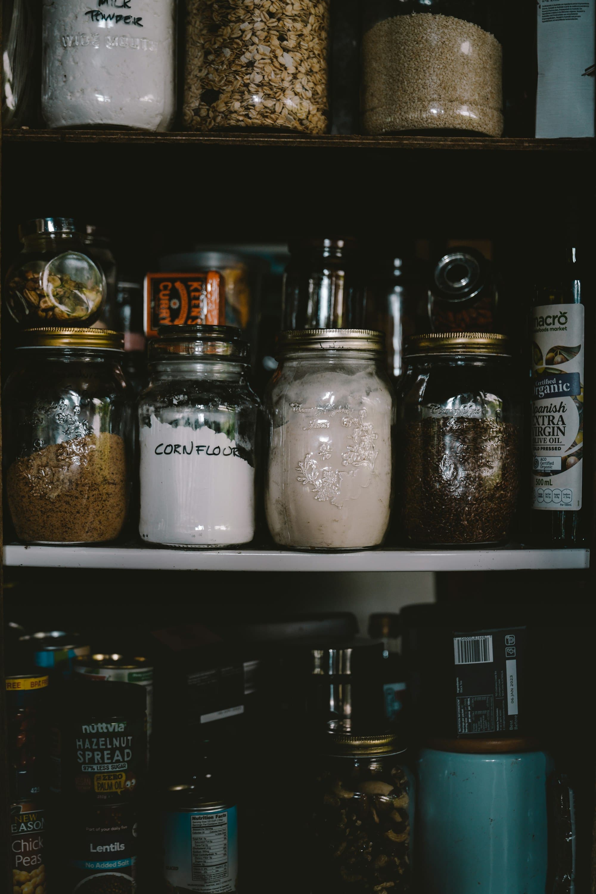 Glass storage jars of dried food on a kitchen shelf